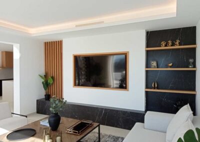 Salón minimalista con TV. Tonos mármol negro, blanco y madera.