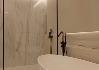 Baño minimalista con ducha y bañera. En tonos mármol, blanco y negro.