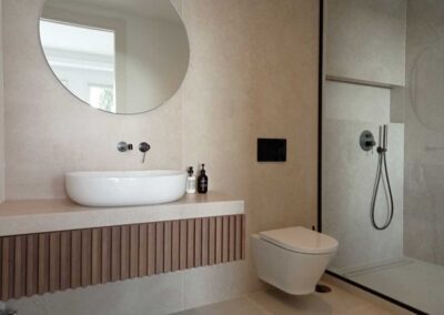 Baño con ducha acabado madera, negro y mármol. Estilo minimalista.