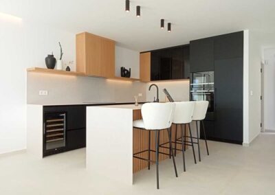 Decoración de cocina con isla estilo moderno con tonos madera, blanco y negro.