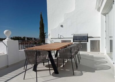 Terraza con mesa comedor y barbacoa, estilo moderno.