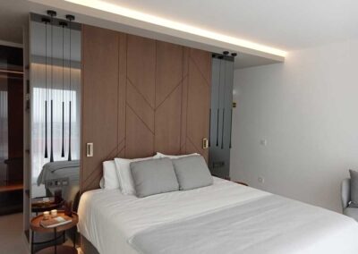 Dormitorio con cabecero de madera y espejo. Decorado en tonos grises.