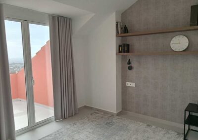 Esquina de dormitorio con alfombra gris.