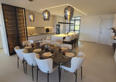 Decoración salón- comedor con cocina americana e isla. Todo con tonos blanco, negro y madera. Estilo moderno.