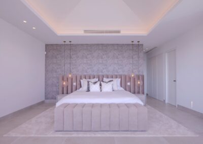 Dormitorio elegante con cabecero textil de terciopelo en tonos grises.