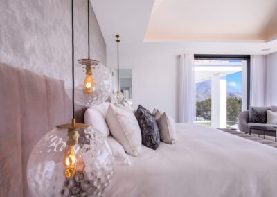 Dormitorio amplio decorado con tonos grises y lámparas modernas.
